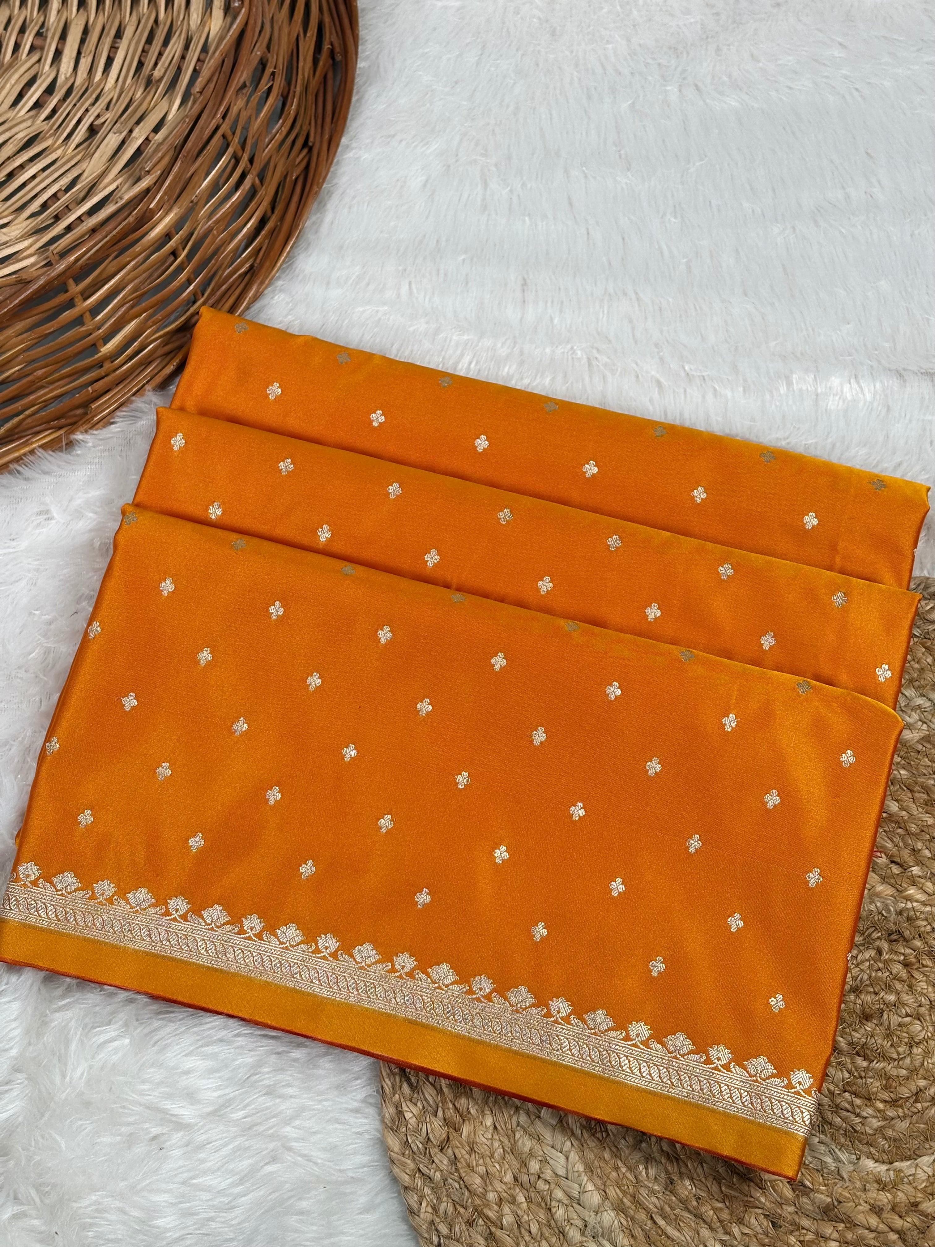 An orange silk saree with small gold floral motifs and a decorative border.