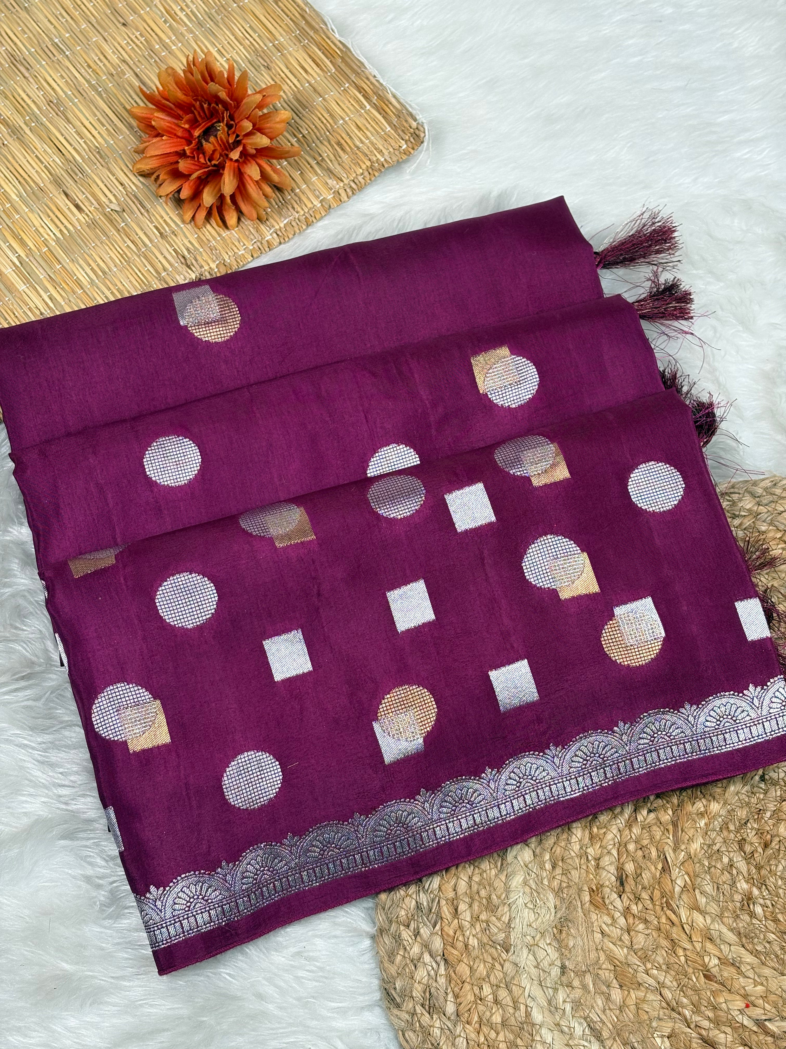 A folded deep purple chinya silk saree with alfi mina geometric motifs, displayed on a white faux fur surface with decorative props.