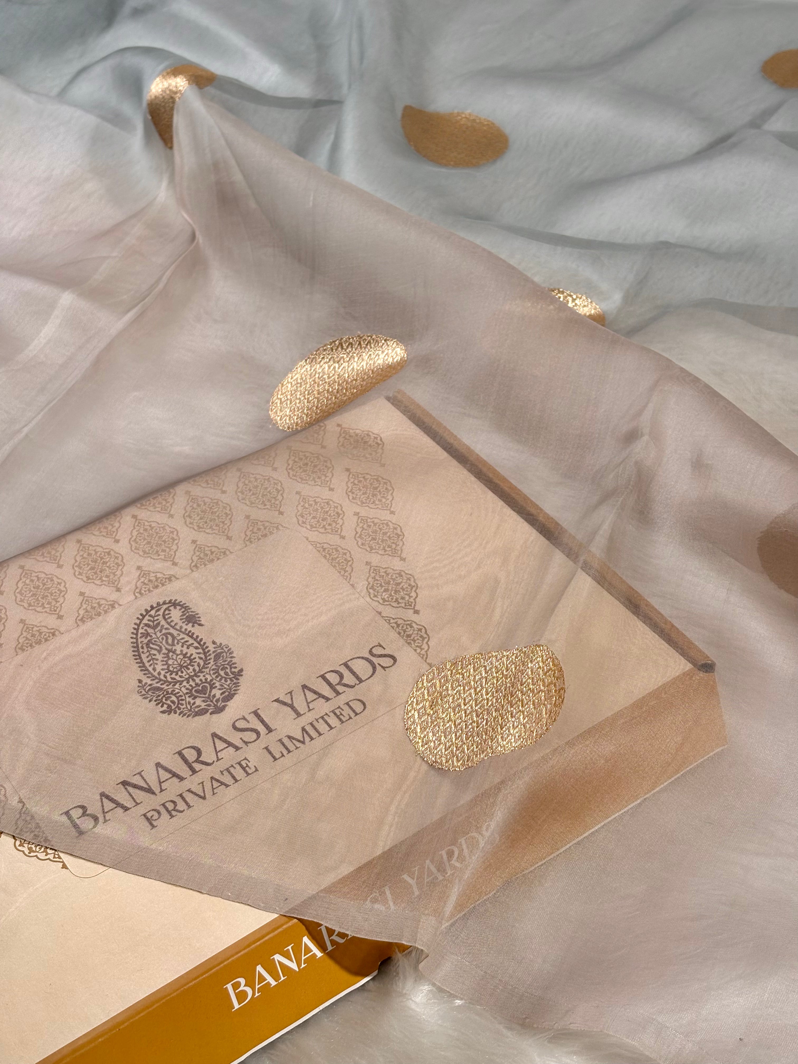 pure kora organza silk saree with a decorated with gold polka dots, draped over its branded packaging box.