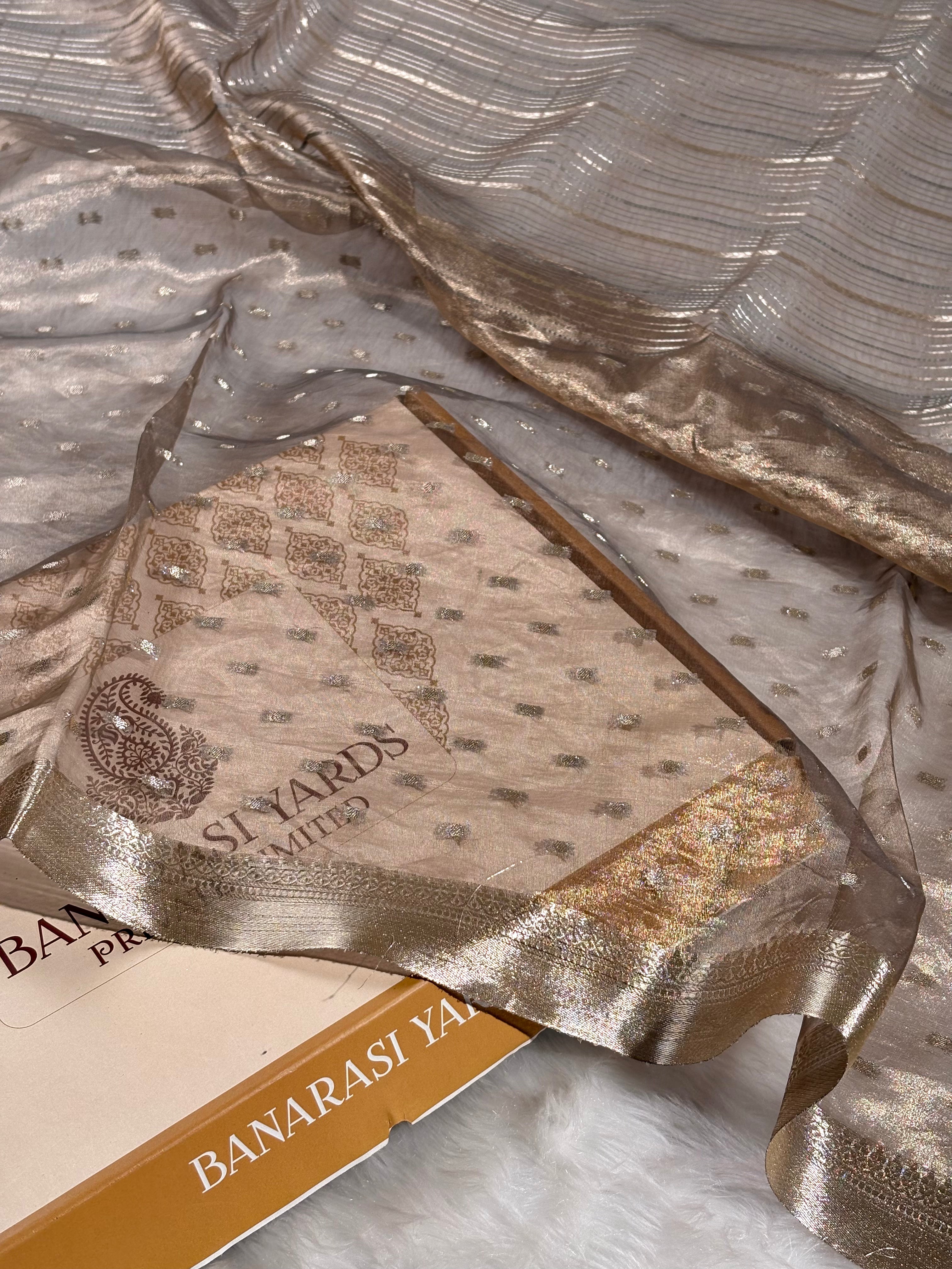 pure tishu silk saree with a metallic gold border, draped elegantly over a white faux fur surface.
