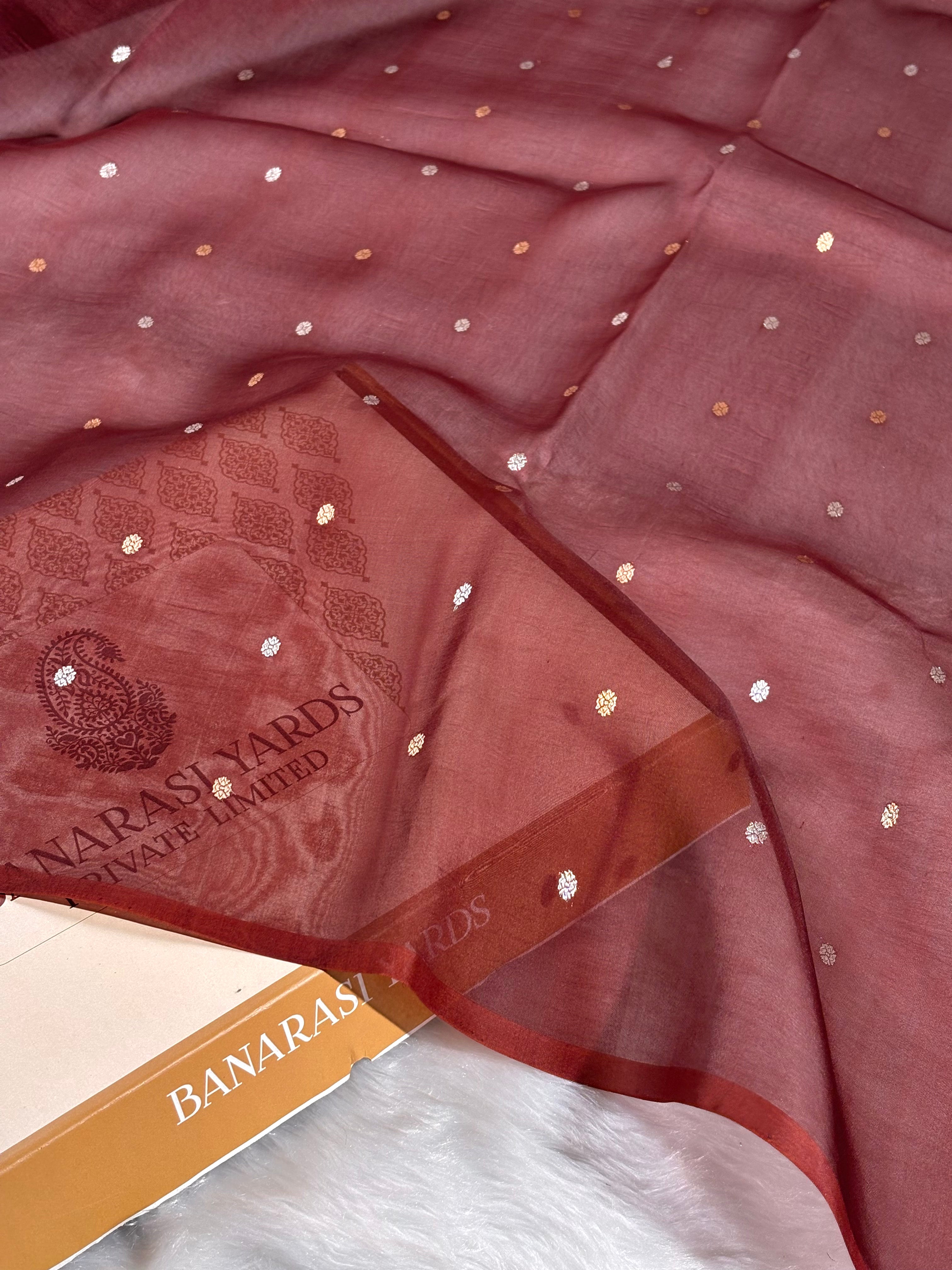 A close-up of a dusty rose pink saree with small scattered metallic silver and gold dots, featuring a matching printed border with the brand name 'BANARASI YARDS PRIVATE LIMITED'.