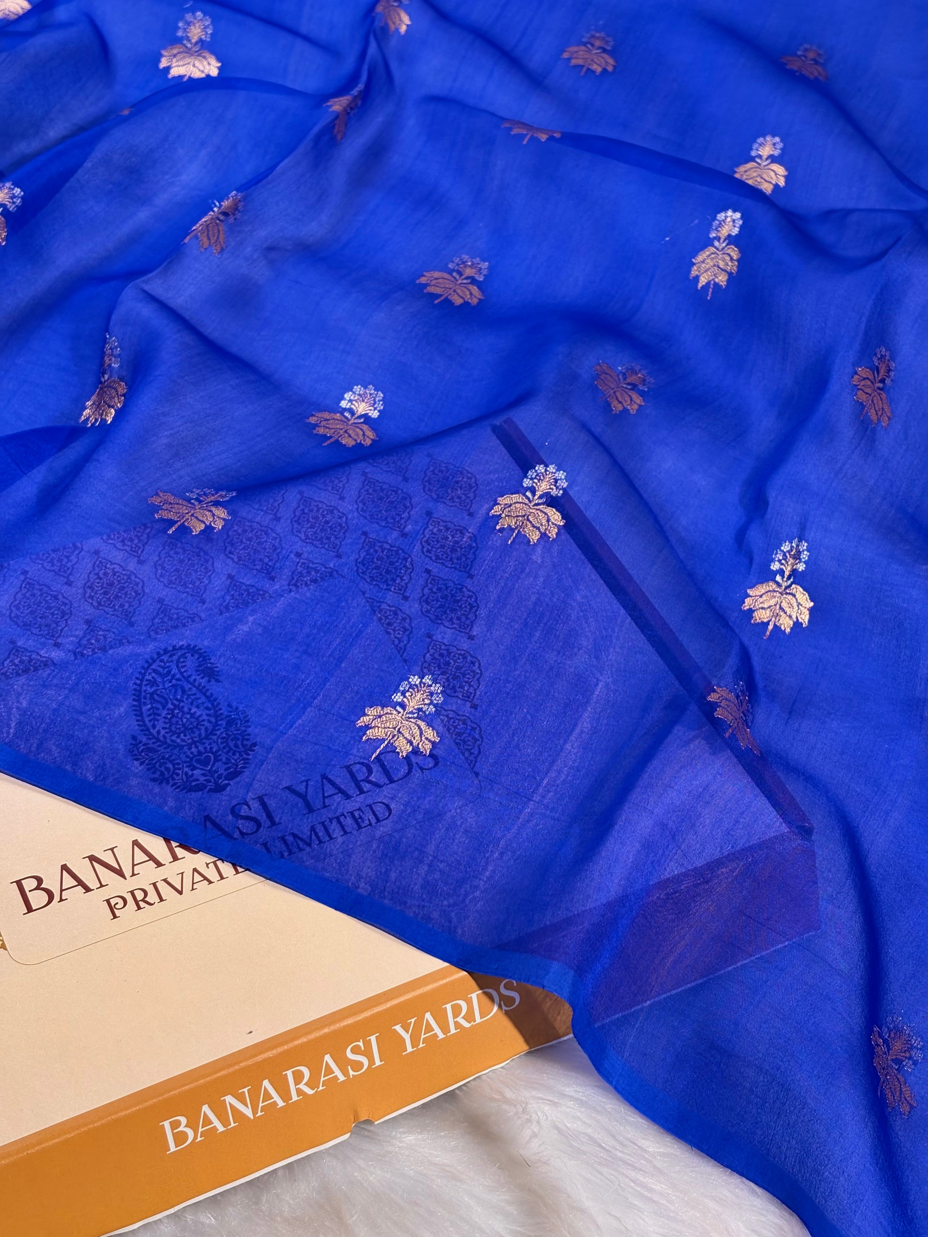 A royal blue sheer organza saree with alfi mina floral motifs, draped over a Banarasi Yards box visible in the lower left corner.