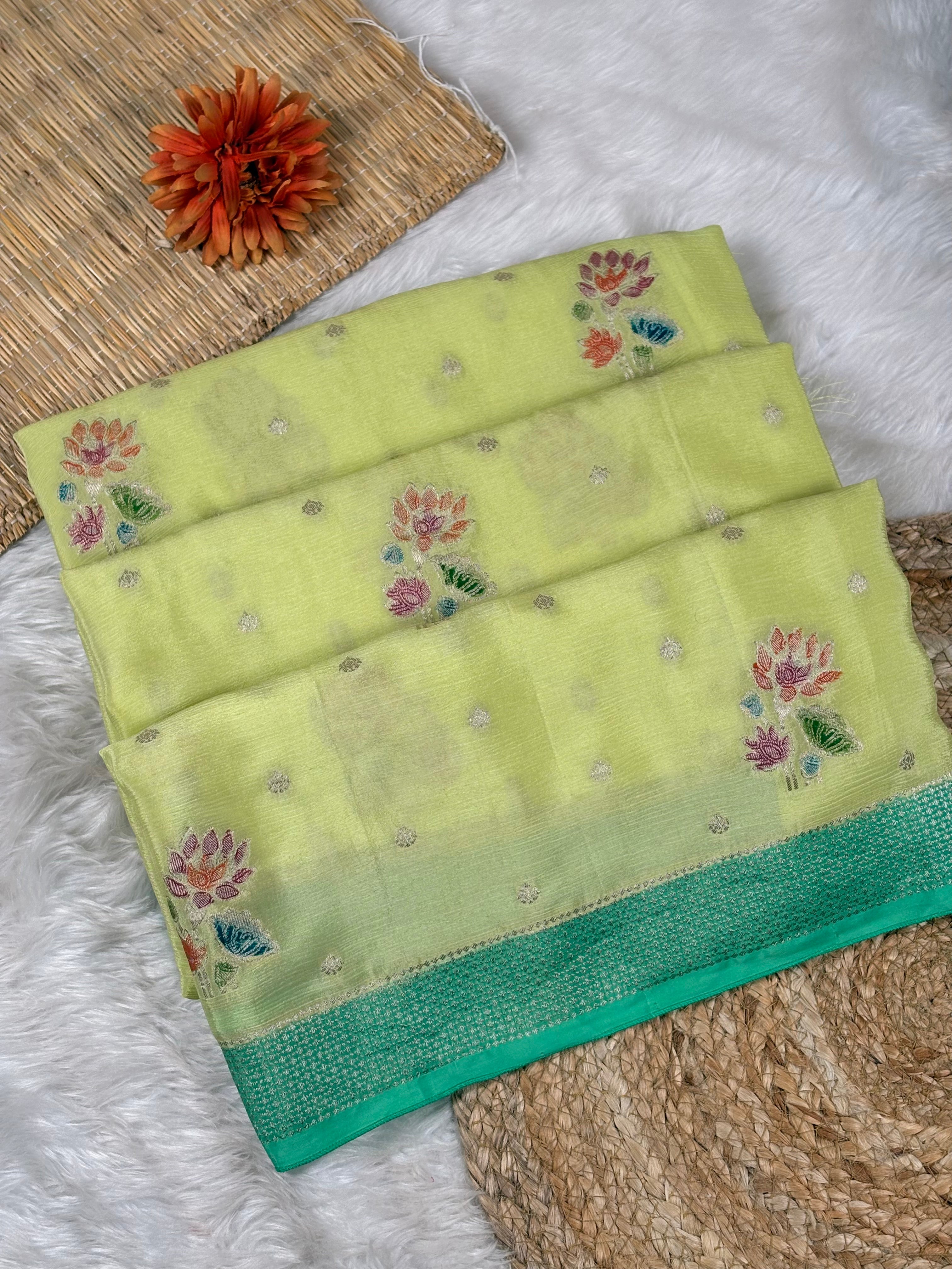 Chinon Silk Mina Banarasi Saree. Crafted from lustrous chinon silk, this saree features delicate hand-brushed mina work that adorns the pallu and borders with intricate floral motifs in gold and jewel tones.