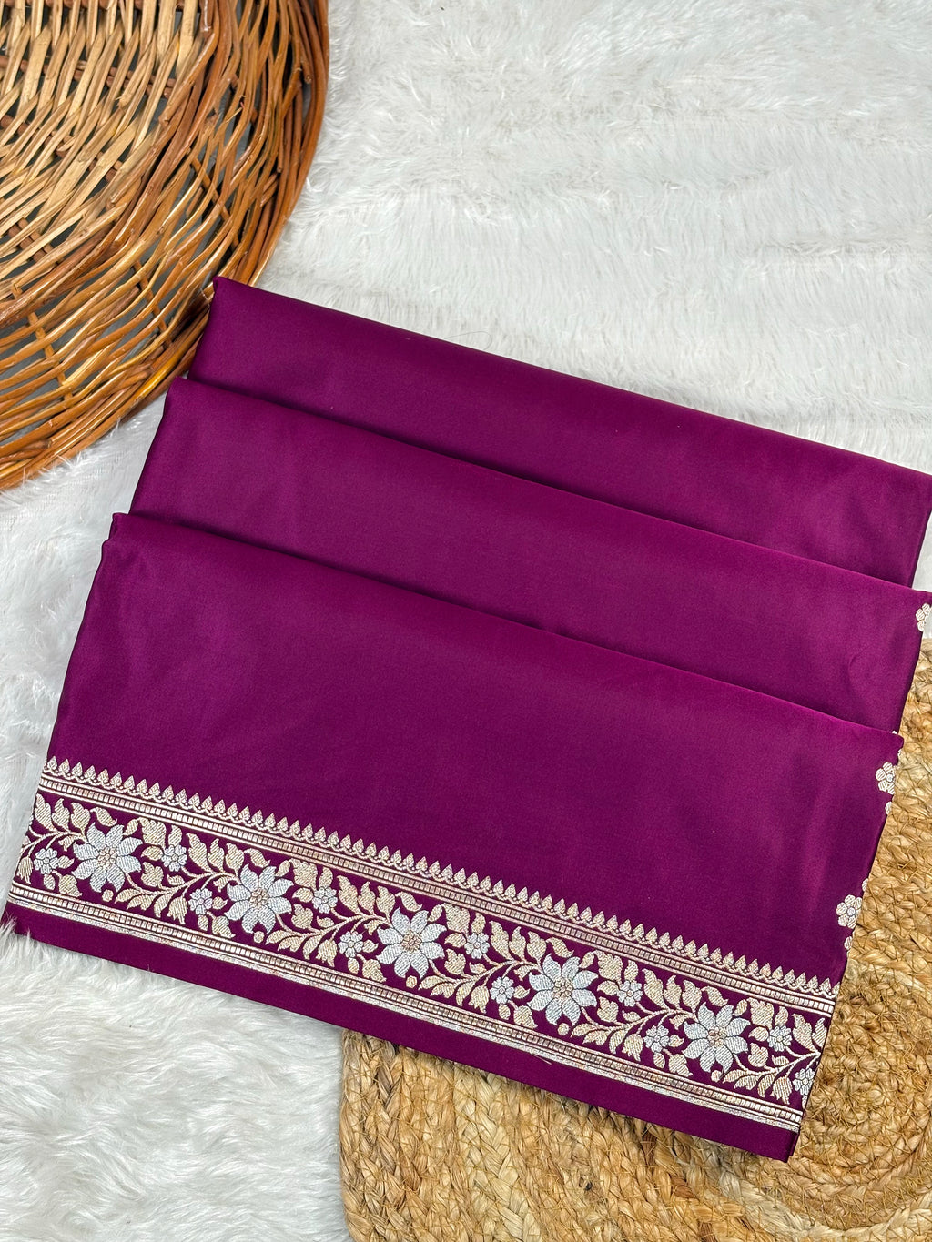 mashru katan wine purple saree, featuring a detailed sona rupa floral border, displayed on a white faux fur surface with a basket.